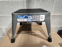 Front view of gray Cosco step stool showing sticker with model and height information.