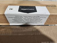 Photo of the Amazon Basics branded box label showing product name, weight support, and multiple languages.