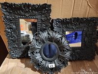 Set of three decorative mirrors with black ornate frames, two rectangular and one round, shown together.