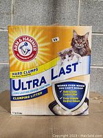 Front of Arm & Hammer Ultra Last Clumping Litter box showing branding, product features, and two cats pictured.