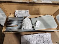 Unassembled metal rods, plastic connectors, fabric shelves, and assembly instructions inside original box