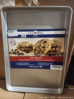 Photo of a new USA Pan commercial bakeware half sheet pan with label showing size and features.