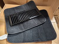 Black plastic drying rack placed on two black drying mats, all arranged on a cardboard box.