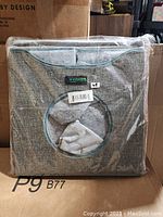 View of the Goopaws gray foldable cat condo in its packaging, showing the front with circular entrance and teal trim.