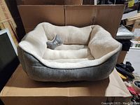 Full view of gray and beige cuddler dog bed with star-shaped plush toy inside.