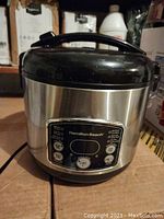 Front view of Hamilton Beach stainless steel rice cooker with black lid showing control panel.