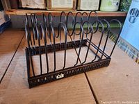Photo showing black metal adjustable organizer rack from front angle with multiple slots for pots and pans