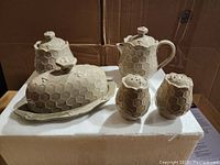 Five-piece Temptations Completer set with two pitchers, butter dish with lid and plate, and salt and pepper shakers, all ceramic with honeycomb texture and bee decoration.