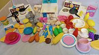 Wide view of entire collection showing sink, stove, various dishes, assorted play food items including corn, chicken legs, and grapes, along with utensils in assorted colors