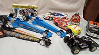 Photo showing nine vintage collectible model cars including 3 blue dragsters, race cars, hot rods, and the boxed Dale Earnhardt telephone
