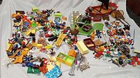 Wide angle photo showing scattered vintage Playmobil pirate ship and zoo themed figures and accessories on a white background.
