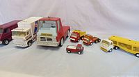Front and side view of all seven metal toy vehicles arranged in a single row on white background.
