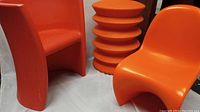 Photo showing three mid-century inspired orange plastic chairs grouped with visible design details.