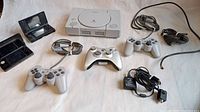 Overview of all items showing Sony PlayStation console, two wired controllers, one wireless controller, power adapter, and Nintendo handhelds