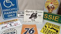 Photo showing blue handicapped parking only sign, white dog-free lawn sign, vintage laundry service sign, Union 76 sign, hot fudge sundae advertisement, and Audi warning sign all arranged together.