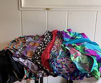 Photo showing seven vintage one-piece swimsuits laid out, displaying various colorful patterns and styles.