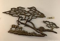 Front view of brass deer wall hanging mounted on wall illustrating the full design including deer, landscape, and tree elements.