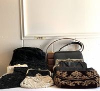 Nine evening clutches and handbags arranged on a white surface with mix of beaded, leather and fabric textures.
