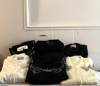 Overview of six vintage beaded and ribbon-embellished knit tops arranged front and back rows