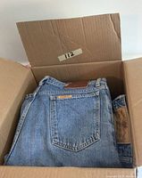 Box filled with folded denim jeans, prominently showing an Edwin jeans pocket with a brown leather brand patch and Edwin label.