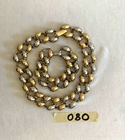 Full view of necklace and bracelet laid flat showing design and color pattern along with tags.