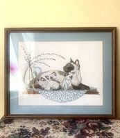 Framed crewel embroidery showing the full artwork with blue mat and wooden frame.