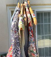 Side view of the dresses hanging closely together showing varied floral prints and fabric texture.