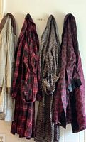 Four vintage men's robes hanging, showing different fabric patterns and colors: beige checkered, red plaid, beige geometric, maroon spotted with black satin trim.