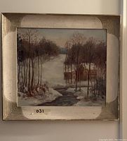 Close-up photo of the winter landscape painting showing details of the snow, trees, stream, cabin, and signature with the wooden Art Deco frame.
