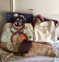 Front view of various vintage handbags and purses including woven bags, leather bags, and clutches stacked together.