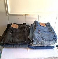 Two stacks of folded denim jeans showing rear pockets and leather patches