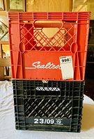 Stacked red Sealtest milk crate on black crate with visible labeling and price tag.