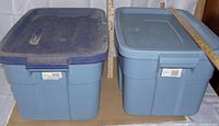 Two blue Rubbermaid Roughneck 53L storage totes with lids, side by side, front view