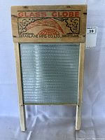 Front view of the vintage Glass Globe washboard showing wooden top with branding and textured glass wash surface.