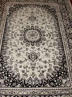Detailed view of the center of the rug showing the intricate medallion and surrounding floral motifs in black and cream color.