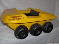 Front-left side view showing yellow body with 'ADVENTURE TEAM VEHICLE' label and black wheels.