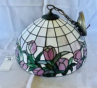 Side view of stained glass dome pendant lampshade showing tulip flower design and metal ceiling mount with hanging chain.