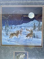 Close-up photo of print showing wolves and full moon under glass with matting and framing details