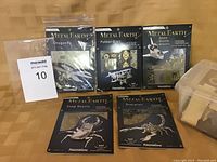 Six Metal Earth model kits displayed with packaging; five kits in unopened original packages including Dragonfly, Fokker D-VII, Space Shuttle Atlantis, Stag Beetle, and Scorpion; one set loose in plastic container.