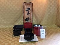 Full array of ceramic items displayed including a tall rectangular plate with tree and animal design, black and red bowls, and square plates.