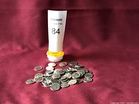 Photo of Canadian 5 cent coins and pill bottle with lot number on burgundy fabric background.