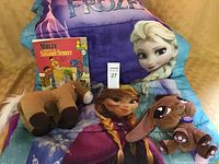 Sleeping bag, two stuffed animals, and Sesame Street book shown together.