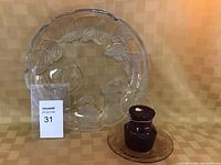 Clear glass serving plate with floral decoration alongside red glass item and dish