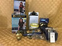 Photo of assortment of handyman items including two Mixing Mate paint mixers, door hardware sets from Schlage, clipboard, measuring tape, and small hardware items.