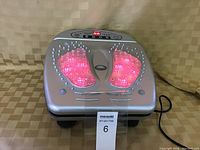 Silver infrared foot circulation massager with red lights on and digital display showing settings.