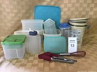 Overview of assorted plastic kitchen storage containers, ceramic canister, and silicone kitchen utensils.