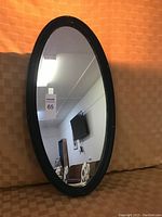 Full view of the oval mirror showing its black frame and reflective surface.