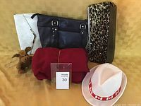 Photo showing three purses (black leather, white textured, black sequin), red blanket, Canada Day hat, and plush moose toy