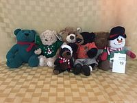 Front view of six decorative stuffed animals including bears and snowman, displayed on a beige background