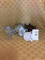 Full view of tea set items including teapot, milkglass cups, honey dispenser, cream and sugar container, cookie dish, and strainer cup.